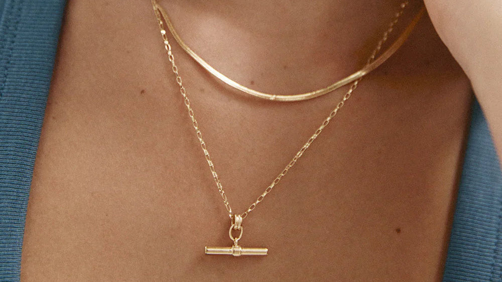 Gold necklaces on a person wearing a blue top